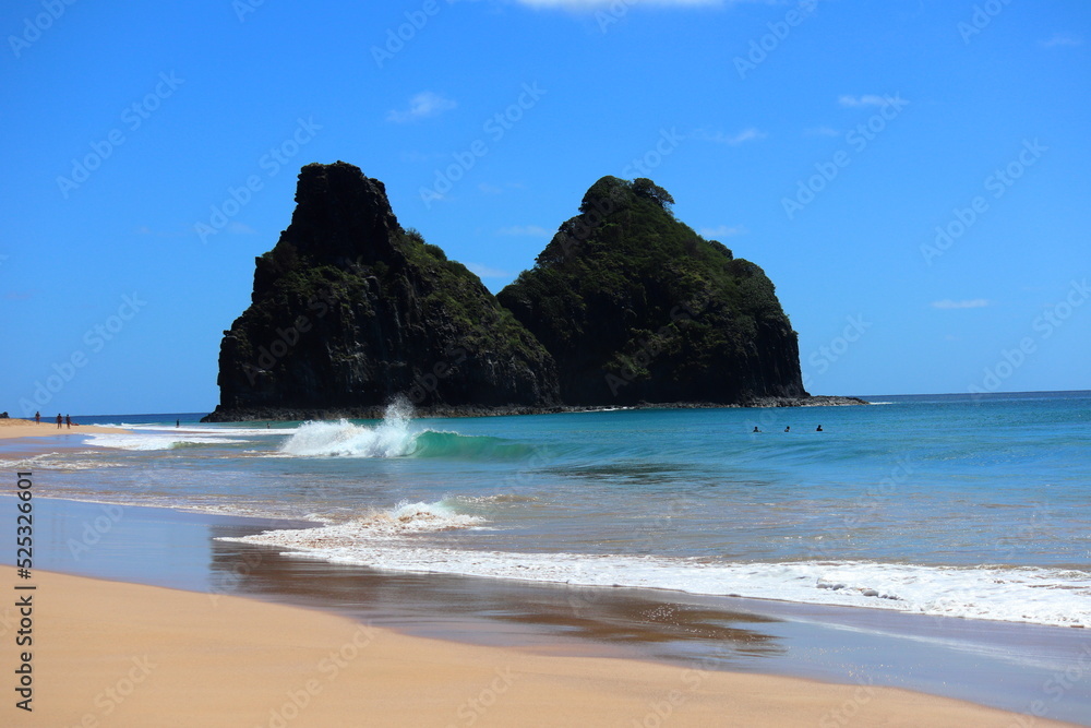 Perfect waves in cristaline waters beside Two Brothers Cliff, Cacimba beach, Fernando de Noronha island, Brazil