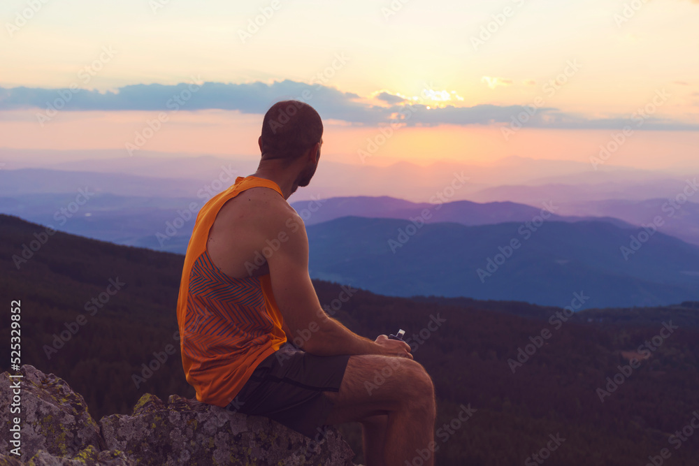 Man Sitting in the Mountain on Orange Sunset Cloudy Sky Background .Orange Sunset in Vitosha Mountain ,Bulgaria 