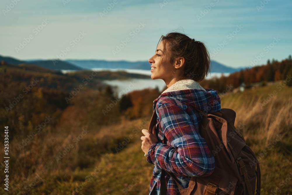 Naklejka premium Outdoors portrait young happy woman with backpack admiring beautiful landscape, hiking on mountain ridge