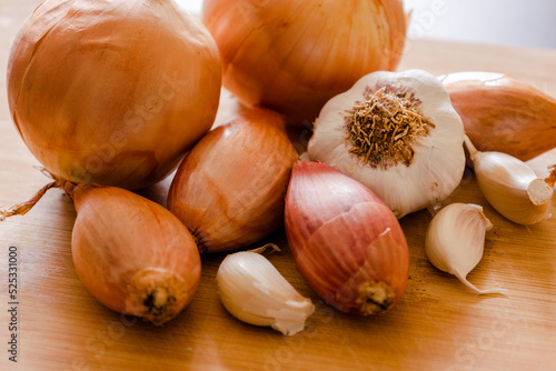 Different types of onion with garlic close up on wooden board