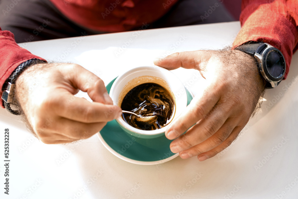 Man holding a pink ceramic cup of hot black coffee in his hands, sitting at the wooden table in a cafe. Close-up photo Man holding a pink ceramic cup of hot black coffee in his hands, sitting at the wooden table in a cafe. Close-up photo