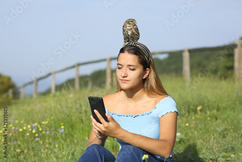 Woman using phone with a bird on head photo