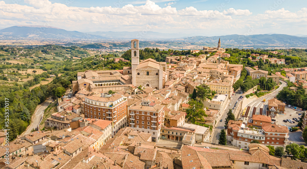 Aerial view of the tiled roofs of the houses of the old Italian city, its roads, as well as the mountains and fields on the horizon