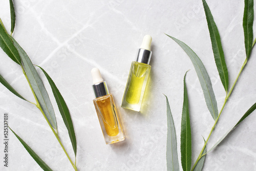 Cosmetic serum bottles with branch leaves on marble background. Beauty concept for face and body care