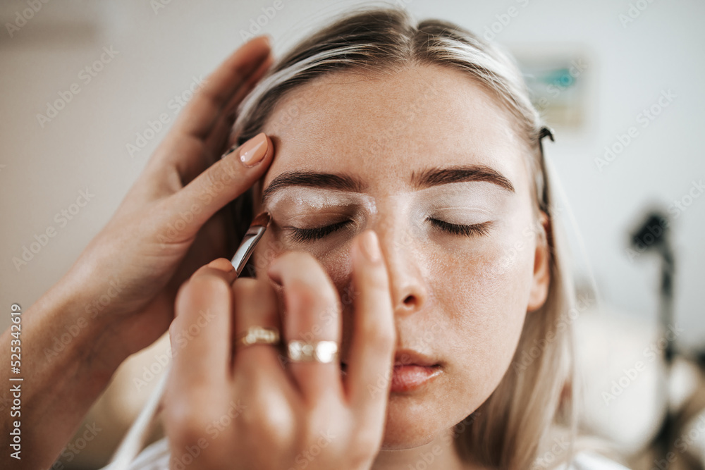 Obraz premium Makeup process. Professional make-up artist using brush on model face. Applying face foundation and tone to skin. Close up portrait of beautiful blonde woman in beauty saloon.