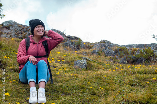 
Atractiva mujer sentada en el césped después de una caminata y disfrutando de la hermosa naturaleza photo