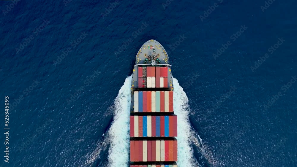 Aerial top down view of a bow from a large container cargo ship traveling with speed over blue ocean