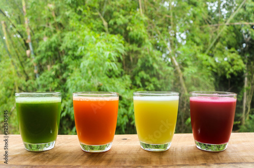 Organic cold pressed fruit and vegetable juices in glass on wooden table at garden. healthy food concept.