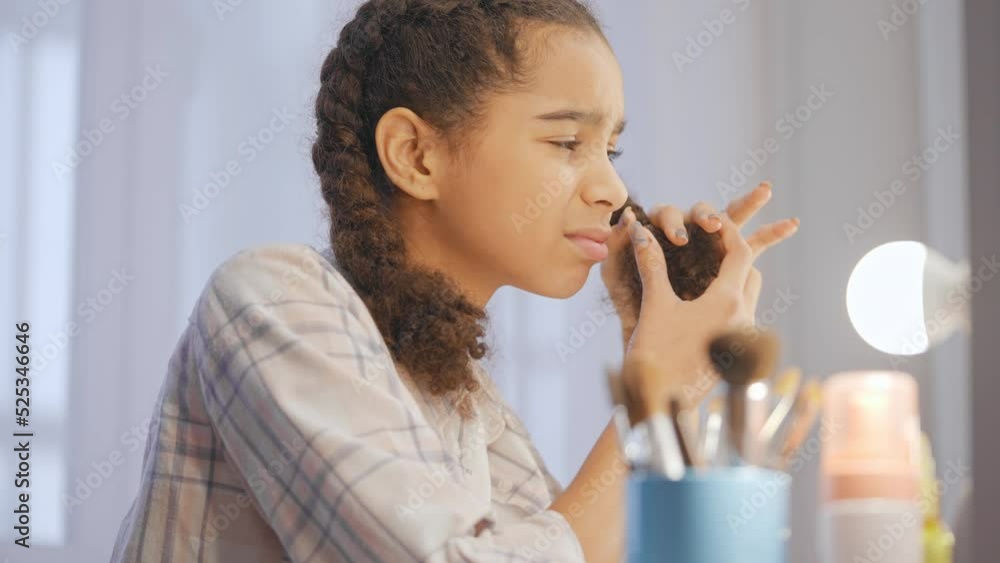 African American teen girl looking in mirror, displeased with weak and dry hair African American teen girl looking in mirror, displeased with weak and dry hair