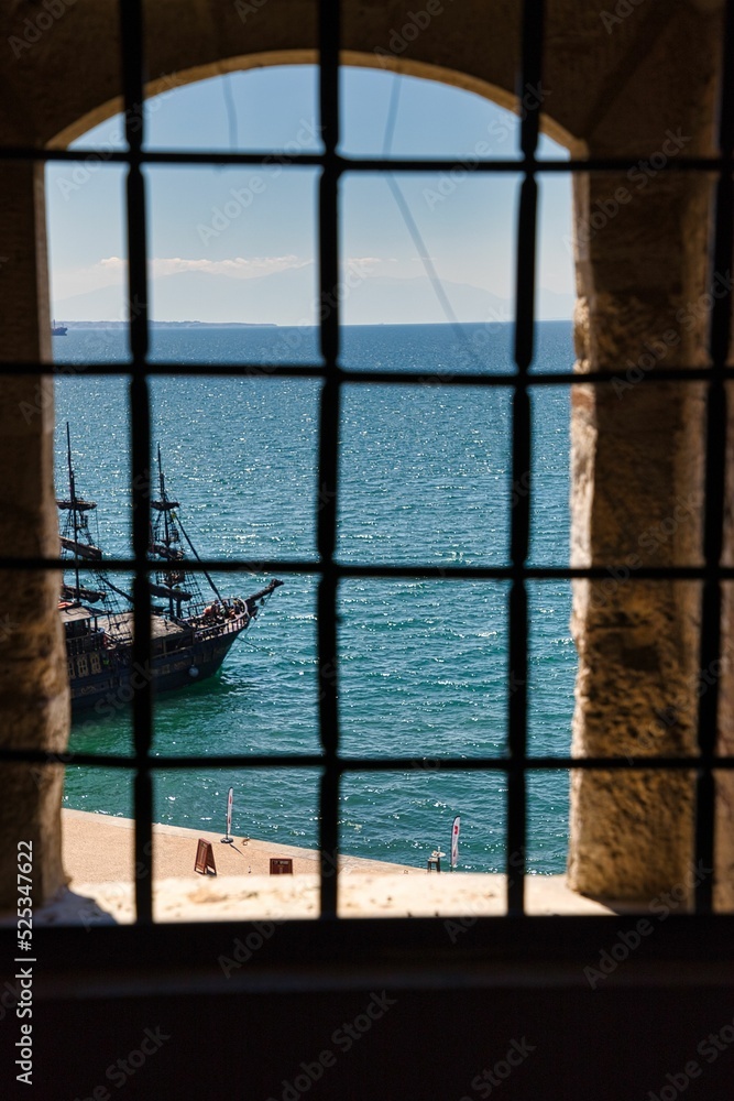 Blick durch ein Gitterfenster aufs Meer und ein altes Schiff Blick durch ein Gitterfenster aufs Meer und ein altes Schiff
