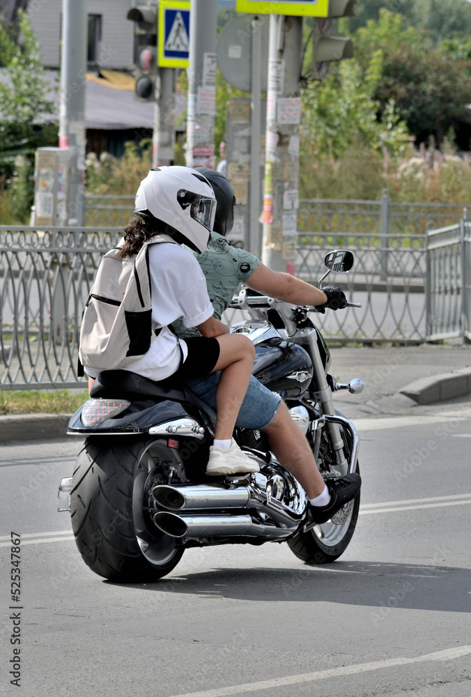 Obraz premium A man and a woman ride a motorcycle down the street on a summer day