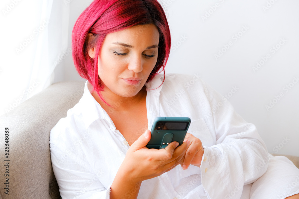 Pretty girl using her smartphone on couch at home in the living room Pretty girl using her smartphone on couch at home in the living room