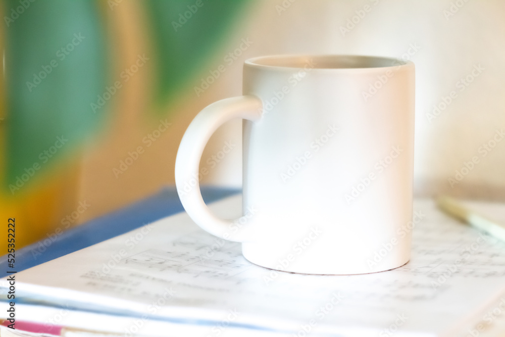 A white mug on a stack of papers