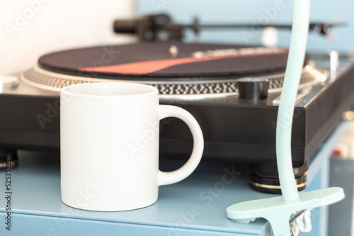 Obraz na płótnie A white mug on a shelf near a vinyl record player w salonie