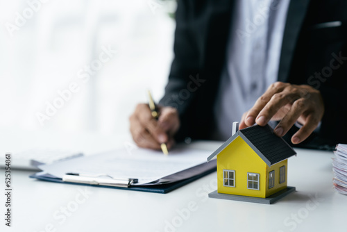 A real estate broker or insurance agent works with home models and home real estate sales contracts within the office, Mortgage loan approval home loan and insurance concept.