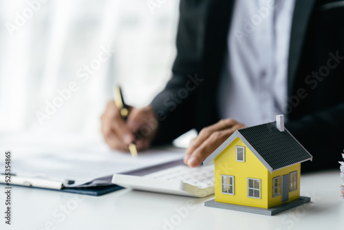 A real estate broker or insurance agent works with home models and home real estate sales contracts within the office, Mortgage loan approval home loan and insurance concept.