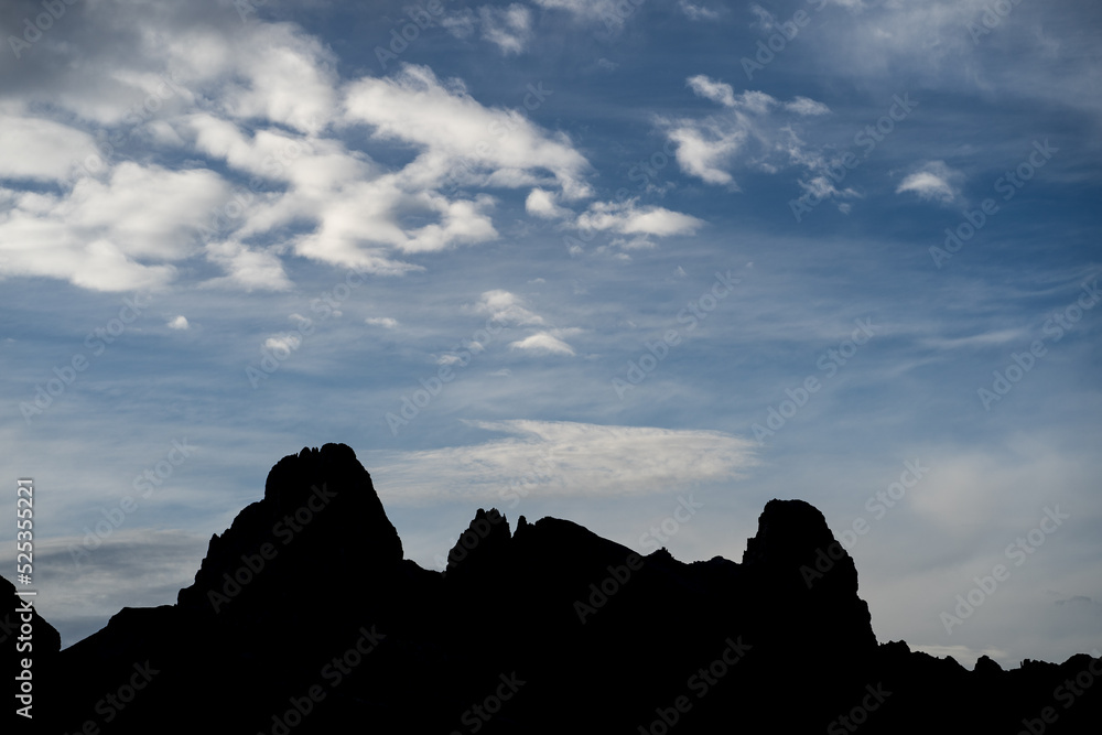 Mountain skyline on horizon. Dark silhouette of mountains against blue and dramatic sky with grey clouds. Outdoor adventure moutain landscape photo.