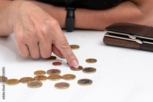 Metal coins from the wallet are counted on the table on a white background. Concept: small pension, poverty, lack of money for living,