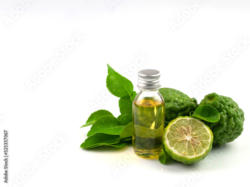 Fresh green kaffir lime herb with essential oil bottle, isolated on white background.