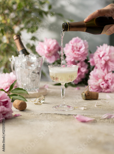Konstfotografi Glass of champagne on concrete grey background with bucket of ice and a bottle of champagne and purple peonies