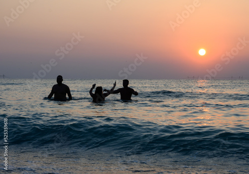People have fun swimming and playing in the waves of the sea. Tourists in the sea at sunrise. © bogdan vacarciuc