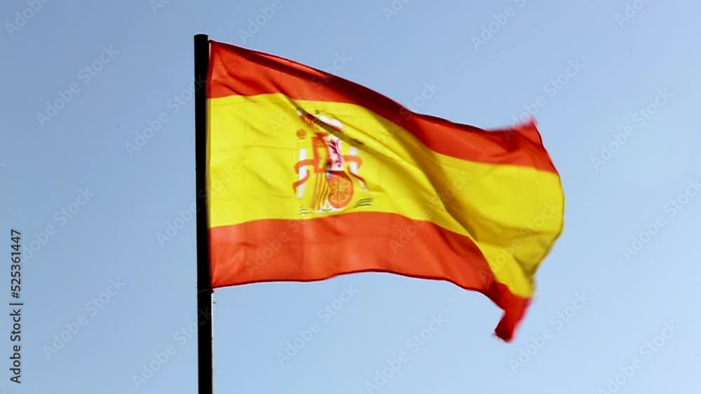 The national flag of Spain waving with slow motion in a blue sky The national flag of Spain waving with slow motion in a blue sky