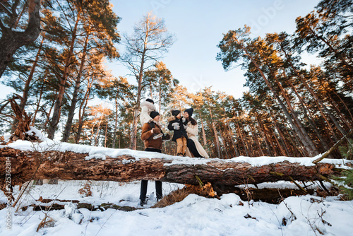 Young family with children walks in winter forest. Wide angle shooting. Winter landscape with coniferous pine forest.