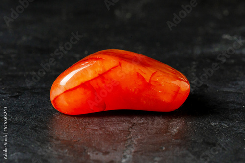 Carnelian mineral on a black concrete background. The concept of using minerals and crystals in astrology and alternative or complementary medicine.