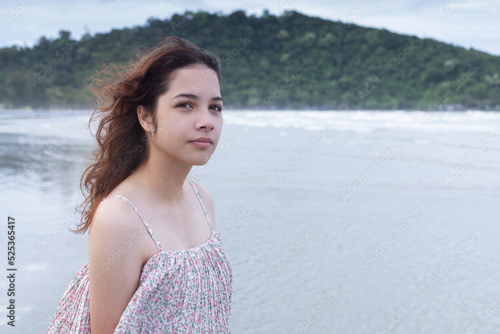 Pretty teen girl walking on the beach in the morning, portrait of young teenager girl with curly hair, cloudy day by the sea Pretty teen girl walking on the beach in the morning, portrait of young teenager girl with curly hair, cloudy day by the sea