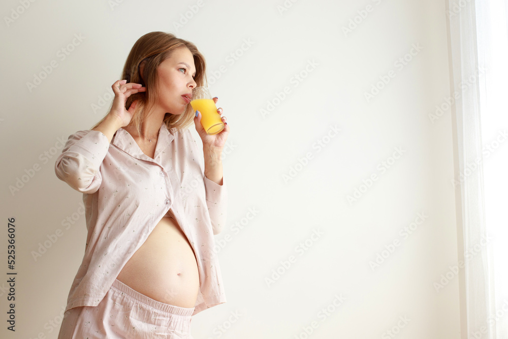 pregnant woman drinking orange juice by the window pregnant woman drinking orange juice by the window