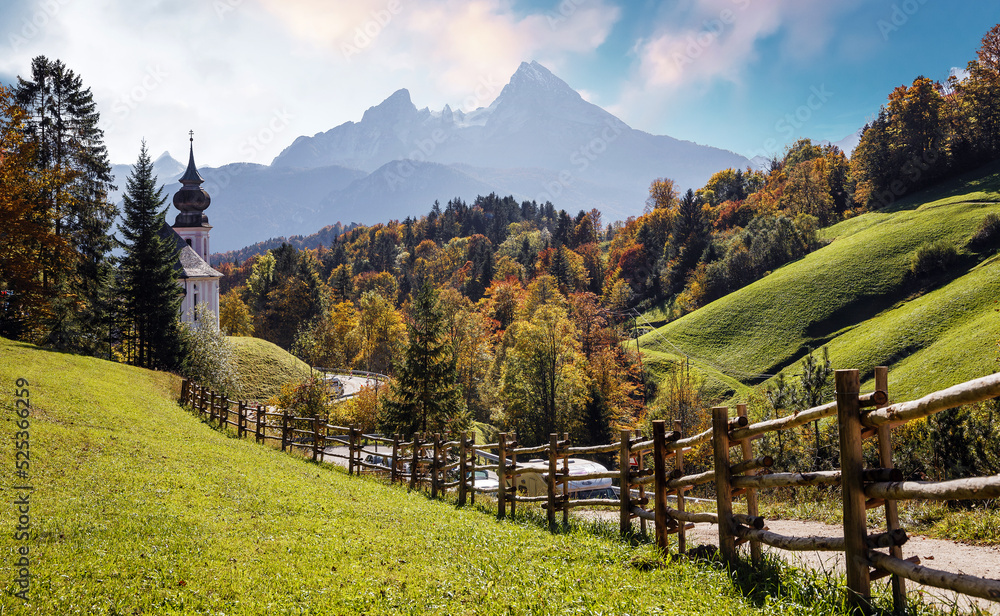 Stunning Autumn landscape during sunset. Scenic panoramic picture-postcard view of famous Maria Gern church in beautiful warm morning light in fall. Vivid atmospheric nature scenery. Nature background