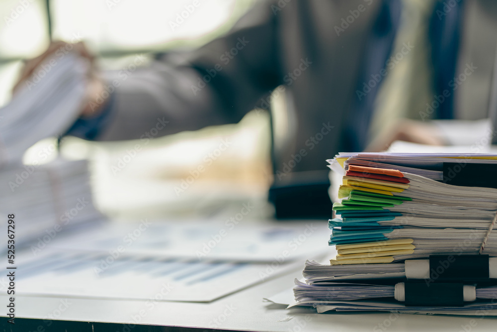 Businessman working in financial accounting with piles of documents on the desk at home work from home concept, business report, pile of unfinished paperwork Businessman working in financial accounting with piles of documents on the desk at home work from home concept, business report, pile of unfinished paperwork