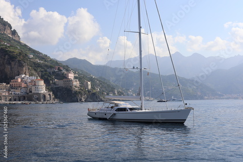 Beautiful seascape with yacht near shore in the sea. Modern sailboat on a sunny summer day.  Sailing near coastline in the Mediterranean Sea. Scenic Amalfi Coast view.