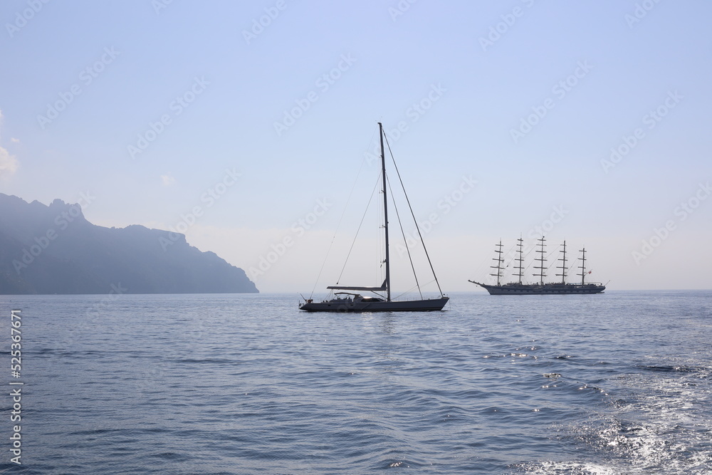 Beautiful seascape with yacht near shore in the sea. Modern sailboat on a sunny summer day. Sailing near coastline in the Mediterranean Sea. Scenic Amalfi Coast view. Beautiful seascape with yacht near shore in the sea. Modern sailboat on a sunny summer day. Sailing near coastline in the Mediterranean Sea. Scenic Amalfi Coast view.