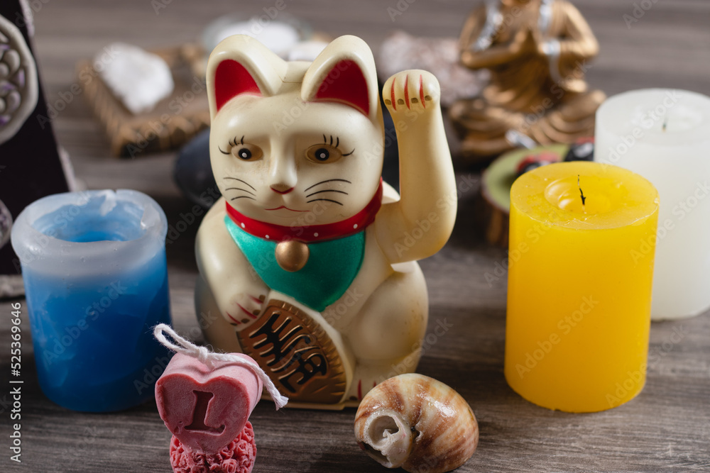 Fortune cat with two decorative candles on a wooden table