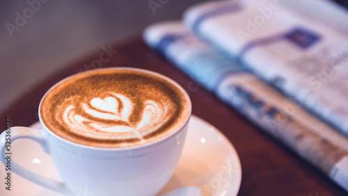 Top view of a Late art coffee cup on blur newspaper background, classic retro warm tone 