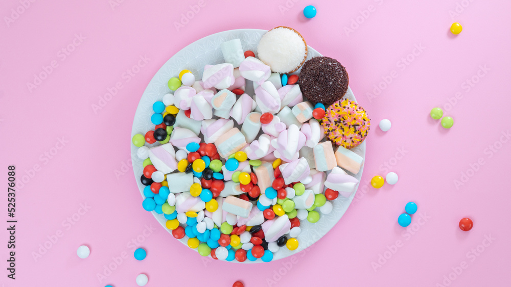 Colorful sweets on a plate on a pink background - sugar food