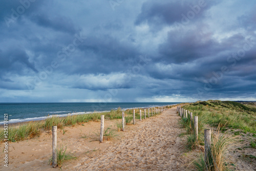 A beautiful sandy path along the ocean. Dark clouds in the sky. North Holland dune reserve, Egmond aan Zee, Netherlands. © Susanne Fritzsche