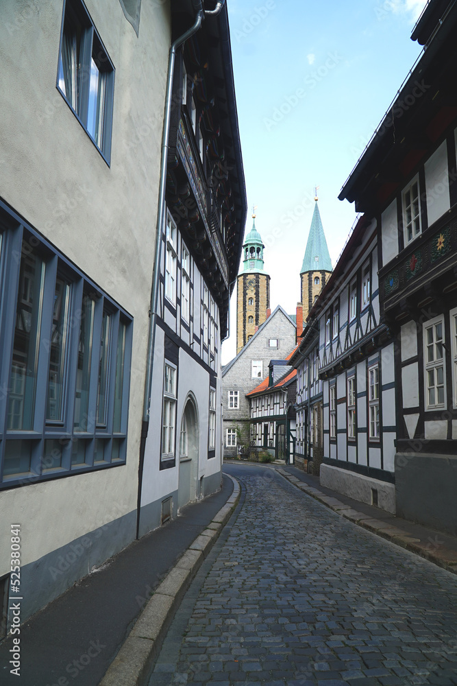 Street view of half timbered facades in the historic old town of Goslar, in background the two towers of Market Church St. Cosmas und Damian. Harz district, Germany, Europe.