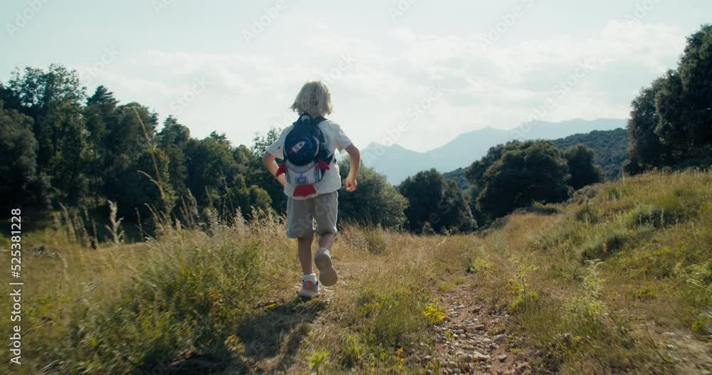 Cheerful carefree children running on countryside road at mountain hike travel. Camera following active child boy with backpack on summertime vacation journey. Concept of explore and healthy lifestyle Cheerful carefree children running on countryside road at mountain hike travel. Camera following active child boy with backpack on summertime vacation journey. Concept of explore and healthy lifestyle