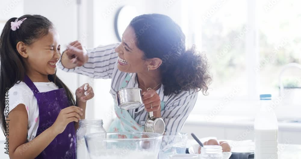 Happy, fun or playful girl baking or cooking food with her mother in the house kitchen. Little child and woman teaching, playing while learning and smile while bonding together at home with love Happy, fun or playful girl baking or cooking food with her mother in the house kitchen. Little child and woman teaching, playing while learning and smile while bonding together at home with love