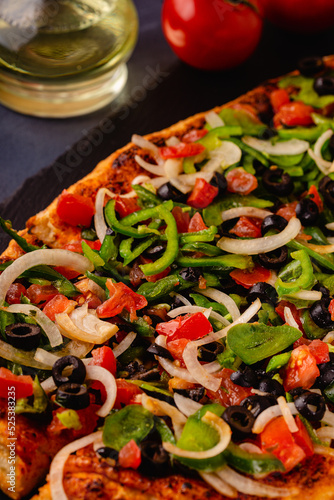 Homemade vegan pizza with tomatoes, peppers, olives, onions.