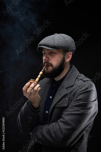 Bearded guy in a coat on a dark smoky background photo