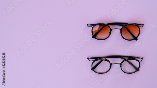 Eyeglasses and sunglasses on a purple background with space for text