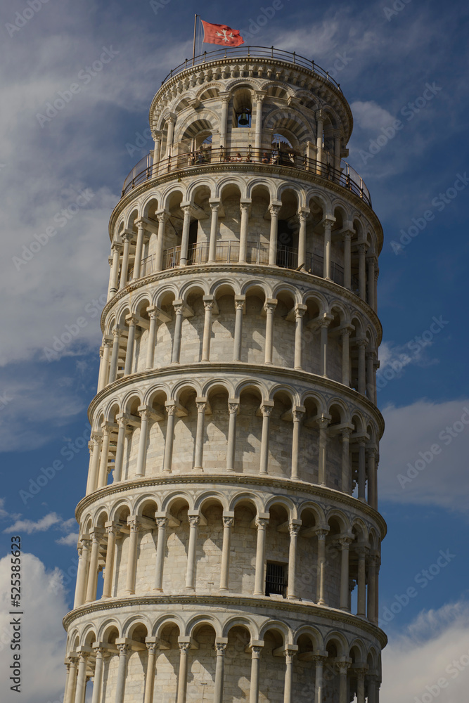 Detailed close-up view of the leaning tower of Pisa, with clouds and flag