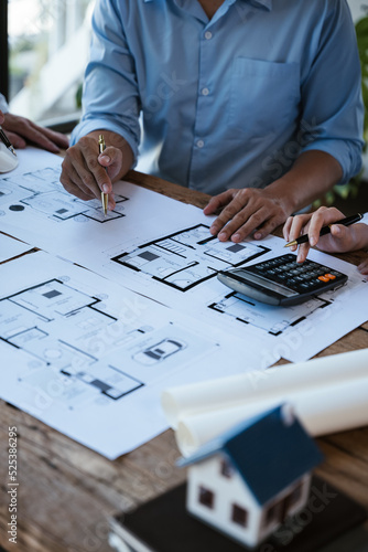 Close up of hands working calculate and brainstorming on paperworks and floor plan drawings about design architectural and engineering for houses and buildings.