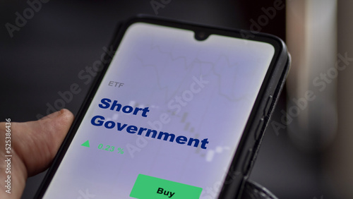 An investor's analyzing the short government etf fund on screen. A phone shows the ETF's prices short government to invest