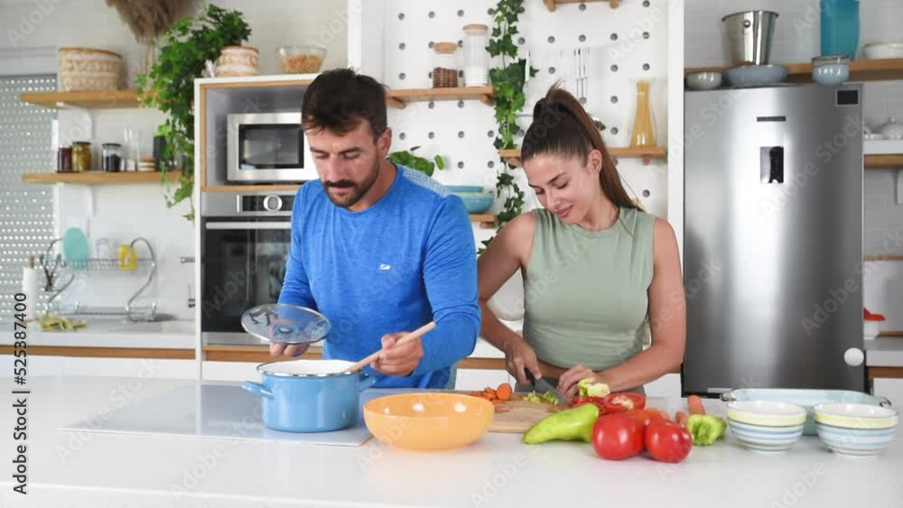 Young sporty man and woman couple cutting and together cooking fresh natural vegetables at kitchen and cooking for healthy lunch. Self care yoga nutritionists having healthy meal after home workout. Young sporty man and woman couple cutting and together cooking fresh natural vegetables at kitchen and cooking for healthy lunch. Self care yoga nutritionists having healthy meal after home workout.