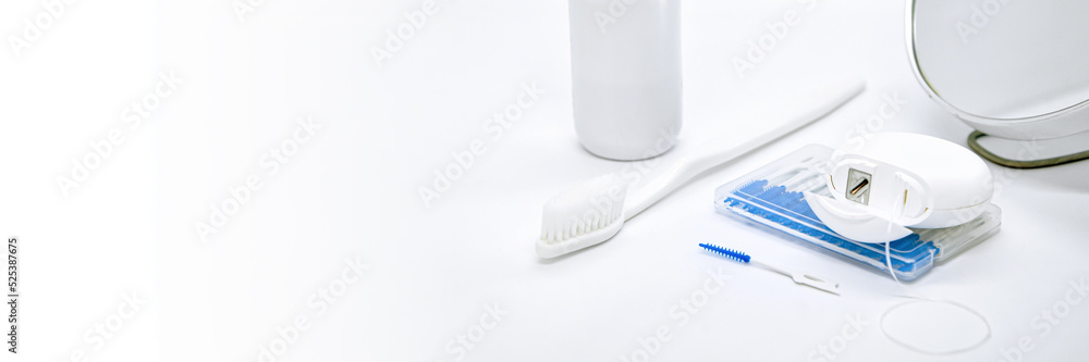 Oral Care: toothbrush, dental floss, brush for cleaning interdental spaces, mouthwash and cosmetic mirror on white background. Concept: dental services, oral hygiene. Banner with free space for text Oral Care: toothbrush, dental floss, brush for cleaning interdental spaces, mouthwash and cosmetic mirror on white background. Concept: dental services, oral hygiene. Banner with free space for text
