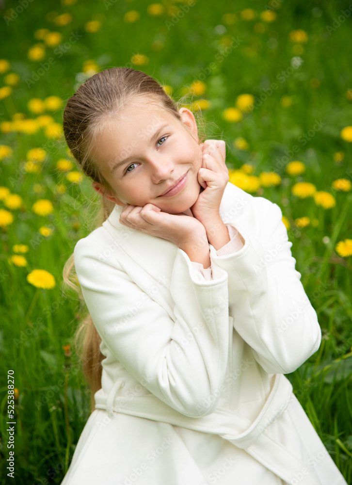 portrait of a little blond beautiful smiling girl with long hair in white coat in the field of dandelions portrait of a little blond beautiful smiling girl with long hair in white coat in the field of dandelions